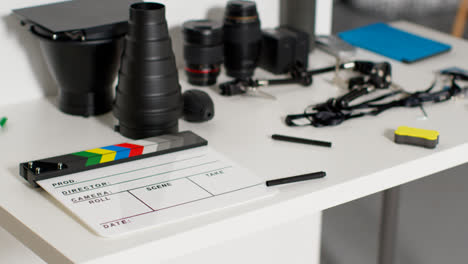 Close-Up-Of-Film-Clapperboard-Or-Slate-With-Camera-Lenses-And-Lighting-Accessories-Shooting-Movie-Or-Video-In-Studio